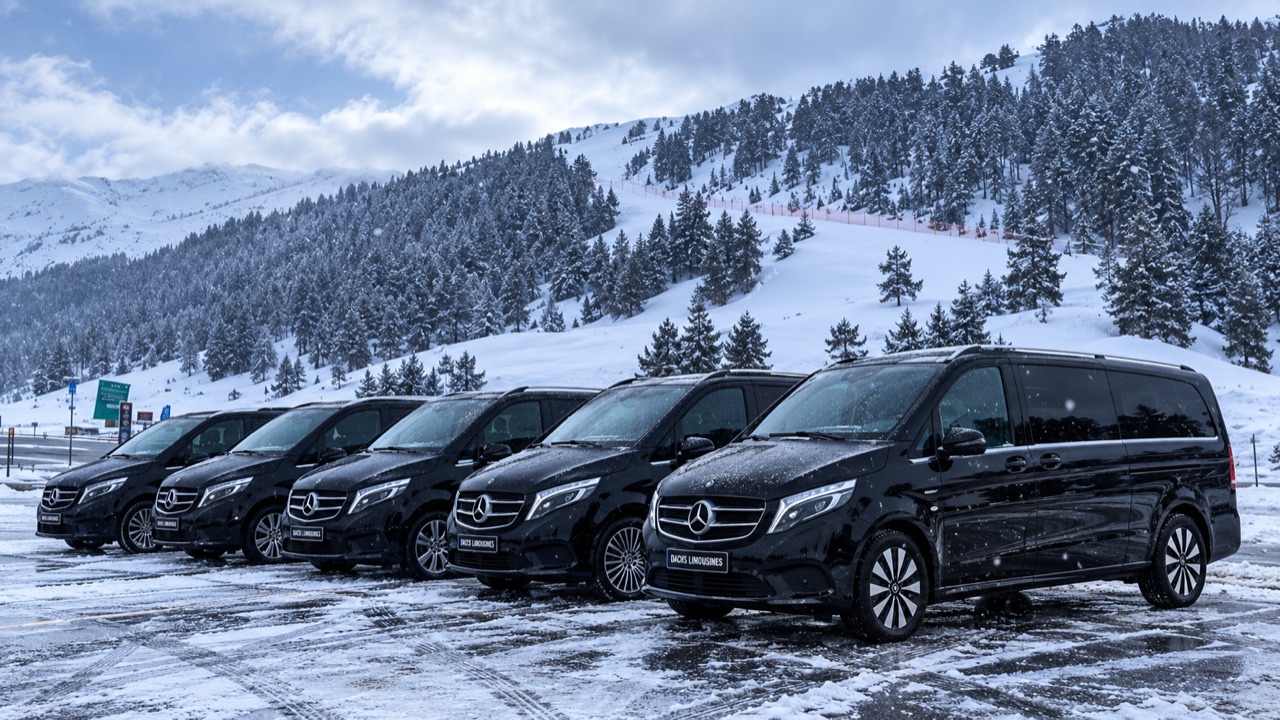 A line of black Mercedes-Benz V-Class vehicles in a snowy mountain landscape